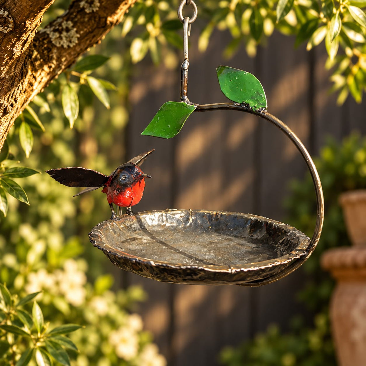 Hangend metalen vogelbad met roodborstje voor in de tuin